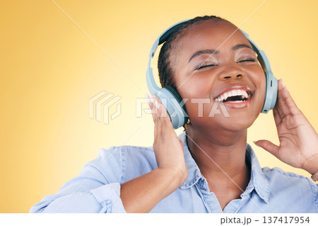 Singer, music and black woman on headphones, smile and listening in studio isolated on a yellow background. Excited, radio and African person streaming podcast, audio and sound, hearing and freedom. Singer, music and black woman on headphones, smile and listening in studio isolated on a yellow background. Excited, radio and African person streaming podcast, audio and sound, hearing and freedom. 137417954