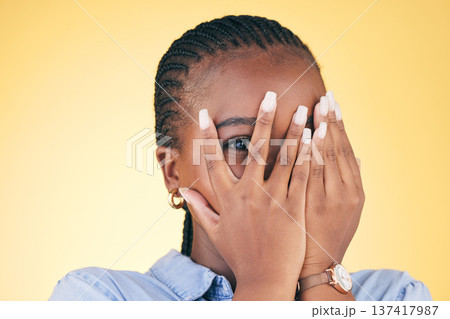 Shy, black woman and hands on face peeping in studio isolated on yellow background. Portrait, fingers and African person embarrassed, scared at danger or fear at horror, social anxiety and spy hiding Shy, black woman and hands on face peeping in studio isolated on yellow background. Portrait, fingers and African person embarrassed, scared at danger or fear at horror, social anxiety and spy hiding 137417987