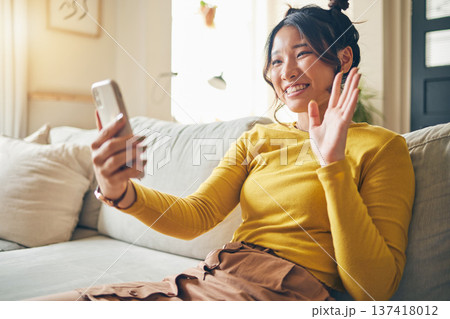 Phone, wave and Asian woman on video call on sofa, communication and conversation in living room. Smartphone, hello and happy person in webinar, virtual chat and online meeting in house discussion 137418012