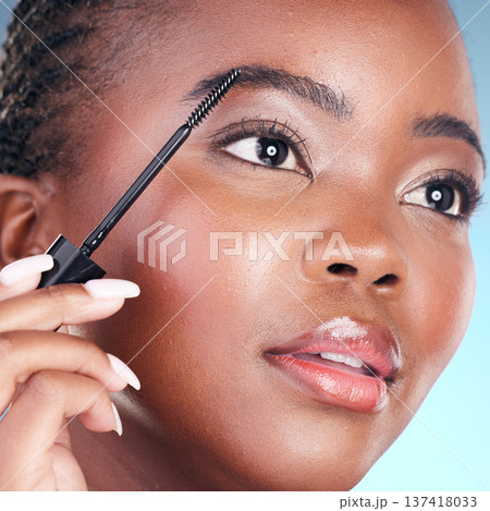 Studio face, black woman and eyebrow mascara, product or cosmetology tools for facial cosmetics application. Beauty routine, brow care makeup and closeup African person on blue background Studio face, black woman and eyebrow mascara, product or cosmetology tools for facial cosmetics application. Beauty routine, brow care makeup and closeup African person on blue background 137418033