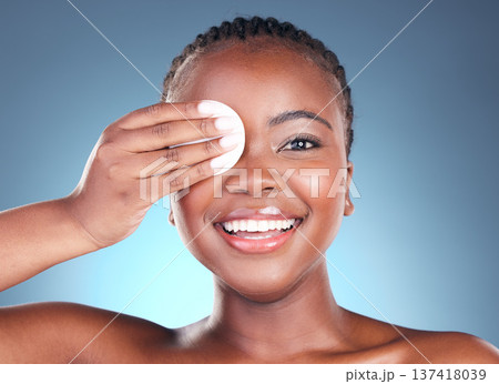 Black woman, portrait smile and cotton pad for makeup removal against a blue studio background. Face of happy African female person with swab in beauty for cleaning, hygiene or facial treatment 137418039