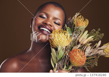 Aesthetic, beauty and protea with the face of a black woman in studio on brown background for natural treatment. Smile, plant or cosmetics and a young model posing for skincare wellness with flowers Aesthetic, beauty and protea with the face of a black woman in studio on brown background for natural treatment. Smile, plant or cosmetics and a young model posing for skincare wellness with flowers 137418280
