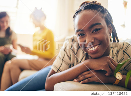 Happy, smile and portrait of black woman relaxing in living room with her friends in her modern apartment. Face, positive and young African female person sitting in the lounge for rest at her home. Happy, smile and portrait of black woman relaxing in living room with her friends in her modern apartment. Face, positive and young African female person sitting in the lounge for rest at her home. 137418421