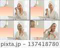 Young woman in bathrobe performing self care routine with eye patches, brushing teeth, applying green clay mask and styling hair in bathroom mirror, mock-up 137418780