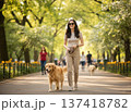 Smiling young woman walking her golden retriever dog in a beautiful blooming park in spring. 137418782