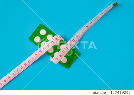 A pills and a measuring tape suggest a journey towards health. A pills and a measuring tape suggest a journey towards health. 137419295