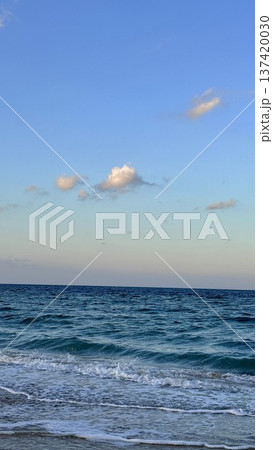 Serene Eventide Glow Over Quiet Sea. Gentle Sunset Illumination Reflecting On Smooth Water Surface. Tranquil Evening Lighting Casting Soft Glow Across Calm Ocean Waves 137420030