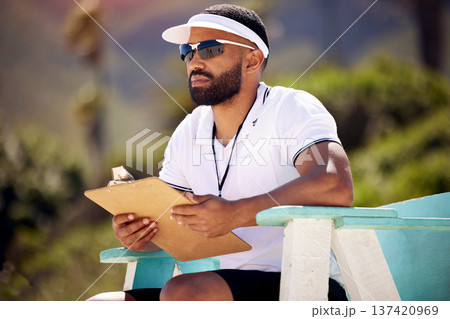 Summer, clipboard and a volleyball referee on the beach in a chair for authority, rules or regulations during a game. Health, documents or competition with a man refereeing a match in the day 137420969