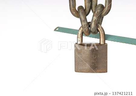 Close-Up of Rusty locked Padlock with Iron Chains and Green Hacksaw Blade on White Isolated Background Representing Security and Vulnerability 137421211