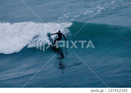 Surfer rides on powerful ocean wave in cold water Surfer rides on powerful ocean wave in cold water 137422105