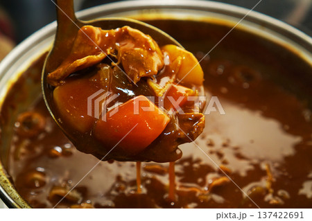 熱々の鍋からポークカレーをすくい上げる 137422691