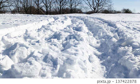 Deep vehicle tracks in the snow after a heavy snowfall. Snowplow tire tracks in the snow on a sunny winter day. 137422878