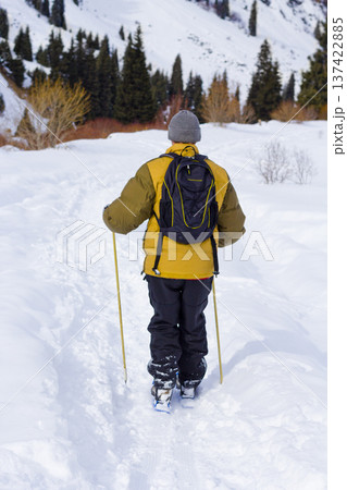 Man walking in snowy mountain forest landscape in winter. Kazakhstan Man walking in snowy mountain forest landscape in winter. Kazakhstan 137422885