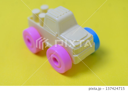 Colorful Plastic Toy Truck with Pink Wheels on Yellow Background Colorful Plastic Toy Truck with Pink Wheels on Yellow Background 137424715