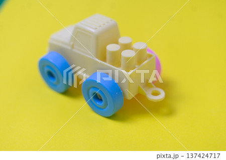 Cream Plastic Toy Truck with Blue Wheels on Yellow Background 137424717