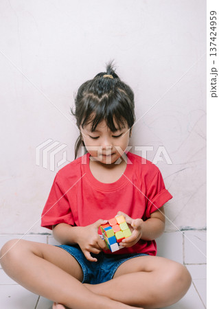 Young Child Concentrating on Solving a Colorful Puzzle Cube Young Child Concentrating on Solving a Colorful Puzzle Cube 137424959