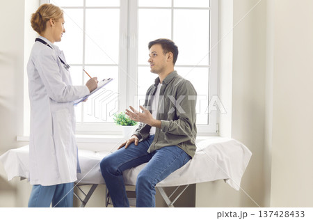 Patient explains health problems and attentive doctor writes down information during consultation. 137428433