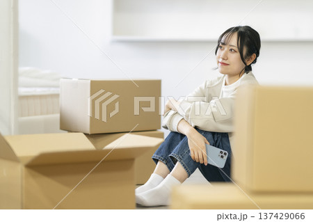 段ボール箱に囲まれて座る若い女性　引っ越し　イメージ 137429066