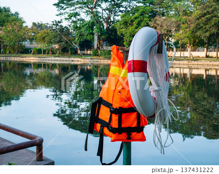 Life Jacket and Buoy: Orange Safety Vest Floating Device Water Rescue Equipment Pool Reflection Background 137431222