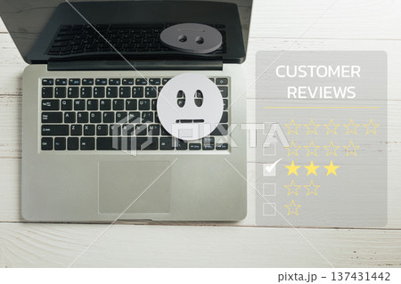 Customer review satisfaction survey captures online feedback and service experience, laptop shows two star rating choice with unhappy emoji face on keyboard indicating low satisfaction 137431442