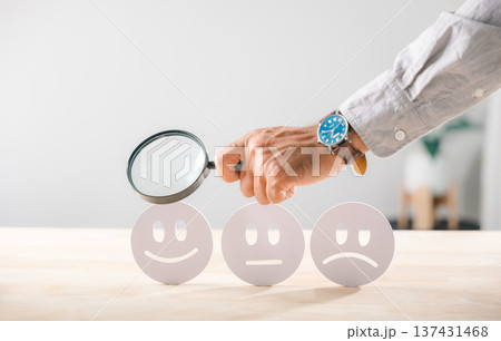 Satisfaction, customer business quality survey face rating, magnifying glass held by hand, examining feedback icons for positive service assessment 137431468