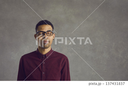 Skeptical African American man looks suspiciously to the side on a gray background. Skeptical African American man looks suspiciously to the side on a gray background. 137431837