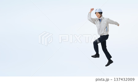 ジャンプするヘルメットをかぶった作業服の男性の全身写真 ジャンプするヘルメットをかぶった作業服の男性の全身写真 137432009