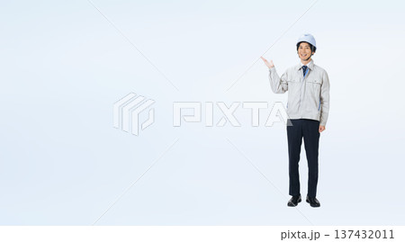 案内するヘルメットをかぶった作業服の男性の全身写真 137432011