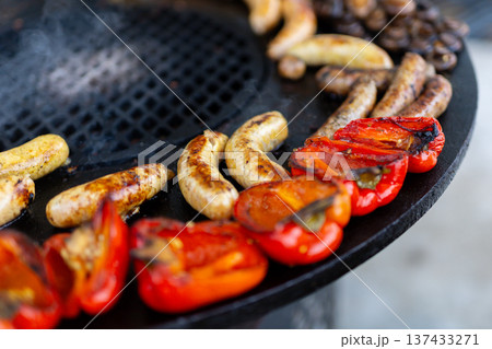 Barbecue with peppers and sausages. Outdoor grill showcasing spicy sausages and peppers 137433271