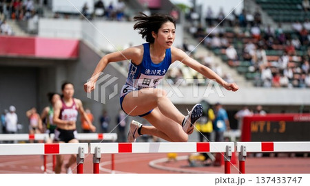 ハードルを跳び越える女子陸上選手 137433747