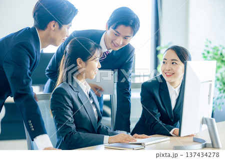 オフィスでパソコンに向かいながらミーティングする新入社員の男女の会社員 オフィスでパソコンに向かいながらミーティングする新入社員の男女の会社員 137434278