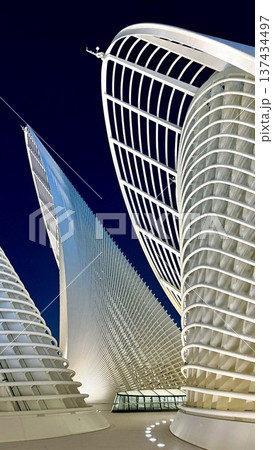 Abu Dhabi, UAE - March 3, 2026: Futuristic Glowing Building. Nightlit Tower Featuring Glowing Shells And Grids. Advanced Bright Edifice Showcasing Curved Surfaces And Grid Lighting Aerial Perspective 137434497