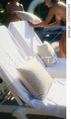 Poolside lounge chair with pillows being arranged 137435164
