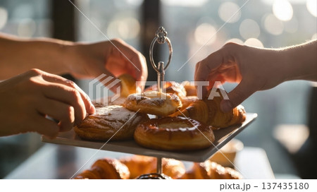 Hands reaching for pastries on tiered dessert stand Hands reaching for pastries on tiered dessert stand 137435180