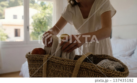 Packing woven basket with towels and fruit at home 137435192