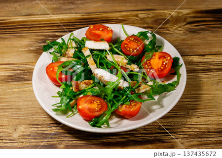 Tasty salad of fried chicken breast, fresh arugula and cherry tomatoes on wooden table Tasty salad of fried chicken breast, fresh arugula and cherry tomatoes on wooden table 137435672