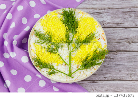 Traditional russian layered salad Mimosa decorated with sprigs of mimosa (made of eggs yolk and dill) on wooden table. Top view 137435675