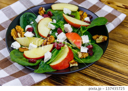 Autumn spinach salad with apple, feta cheese, walnut and dried cranberry on wooden table. Healthy vegetarian food 137435725