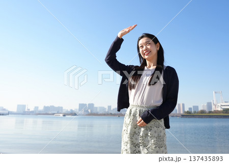 まぶしい日差しをさえぎる若い女性 まぶしい日差しをさえぎる若い女性 137435893