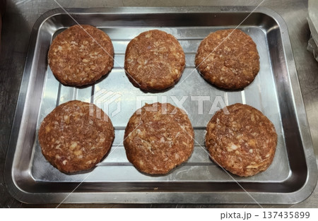 Six Fresh Raw Meat Patties Ready for Grilling on a Metal Tray in a Commercial Kitchen Six Fresh Raw Meat Patties Ready for Grilling on a Metal Tray in a Commercial Kitchen 137435899