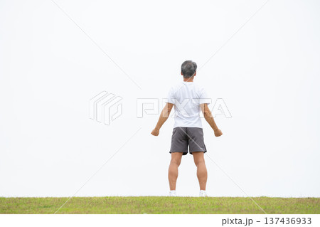 土手で伸びをする男性　後ろ姿 137436933