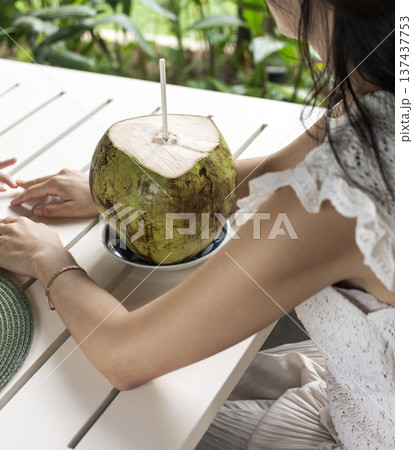 woman drinking fresh coconit in tropical outdoors garden cafe in bali indonesia 137437753