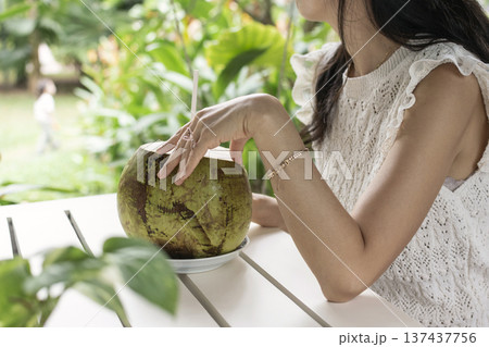 woman drinking fresh coconit in tropical outdoors garden cafe in bali indonesia woman drinking fresh coconit in tropical outdoors garden cafe in bali indonesia 137437756