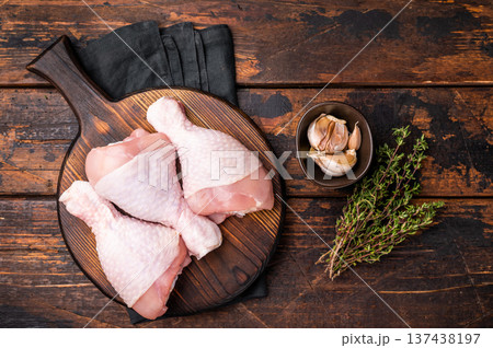 Uncooked poultry drumsticks, raw chicken legs ideal for your favorite recipes, waiting to be seasoned and cooked to perfection. wooden background. top view Uncooked poultry drumsticks, raw chicken legs ideal for your favorite recipes, waiting to be seasoned and cooked to perfection. wooden background. top view 137438197