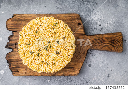 Twisted raw ramen noodles, ready to soak up flavors and bring warmth to your next culinary adventure. grey background. top view 137438232