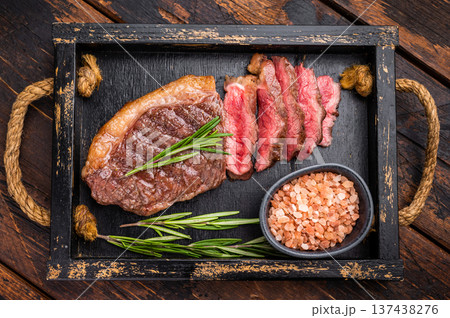 Deliciously charred grilled New York strip or striploin steak with rich marbling, an essential dish for any outdoor gathering. wooden background. top view 137438276