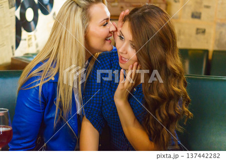 Two women gossiping in pub 137442282