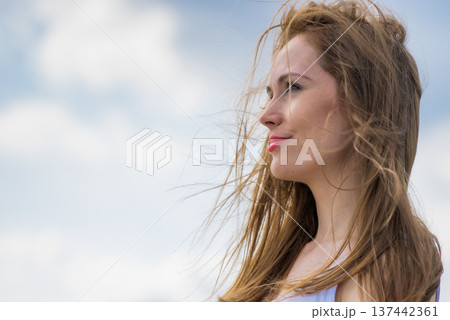 Gorgeous romantic girl outdoors. Brown long hair blowing in the wind against sky. 137442361
