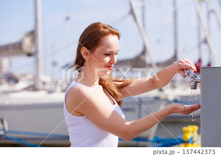 Woman drinking water from tap in marina. 137442373