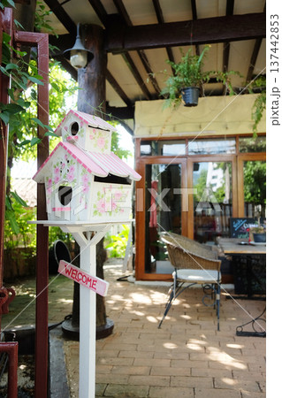 Cute sweet pink and white wooden Birdhouse with with welcome message on wood decorated outdoor of house Cute sweet pink and white wooden Birdhouse with with welcome message on wood decorated outdoor of house 137442853